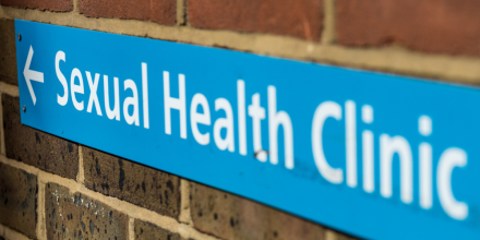 Sign on a brick wall showing the way to a sexual health clinic
