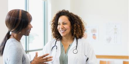 Female doctor smiles while mature female patient speaks