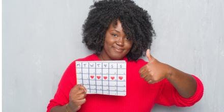 Young African woman holding menstruation calendar