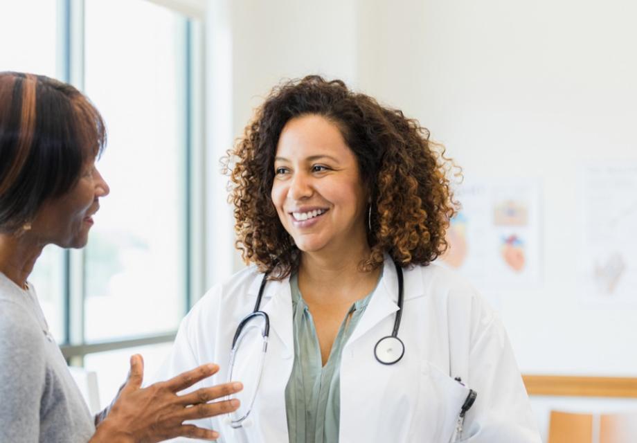 Female doctor smiles while mature female patient speaks